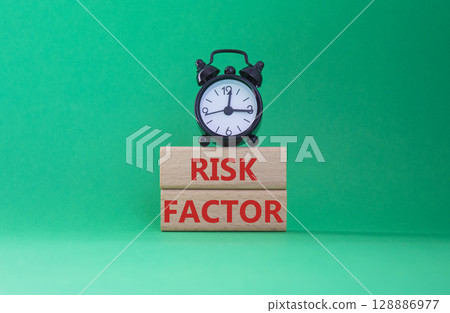 Risk Factor symbol. Wooden blocks with words Risk Factor Beautiful green background with alarm clock. Business and Risk Factor concept. Copy space. 128886977