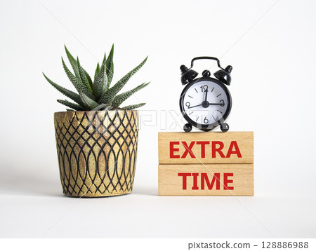 Extra time symbol. Concept word Extra time on wooden blocks. Beautiful white background with alarm clock and succulent plant. Business and Extra time concept. Copy space Extra time symbol. Concept word Extra time on wooden blocks. Beautiful white background with alarm clock and succulent plant. Business and Extra time concept. Copy space 128886988