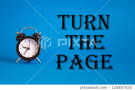 Turn the Page symbol. Concept words Turn the Page on Beautiful blue background with alarm clock. Business and Turn the Page concept. Copy space. Turn the Page symbol. Concept words Turn the Page on Beautiful blue background with alarm clock. Business and Turn the Page concept. Copy space. 128887028