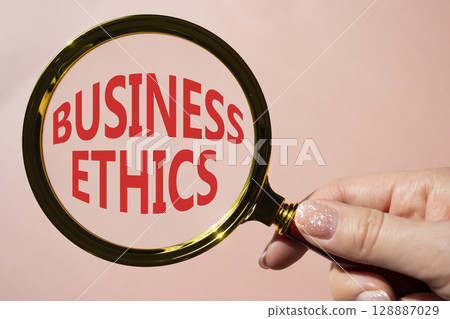 Business ethics symbol. Concept word Business ethics on magnifying glass. Businessman hand. Beautiful pink background. Business and Business ethics concept. Copy space Business ethics symbol. Concept word Business ethics on magnifying glass. Businessman hand. Beautiful pink background. Business and Business ethics concept. Copy space 128887029