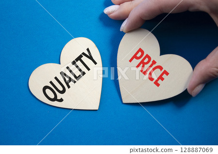 Price or Quality symbol. Concept word Price or Quality on wooden hearts. Businessman hand. Beautiful blue background. Business and Price or Quality concept. Copy space 128887069