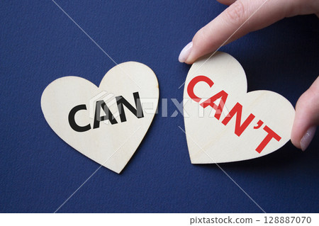 Can or Cant symbol. Concept word Can or Cant on wooden hearts. Businessman hand. Beautiful deep blue background. Business and Can or Cant concept. Copy space 128887070