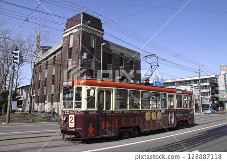 [Logo driver sign blurred person finished] Hakodate City Tram 710 series old-fashioned building and 128887118