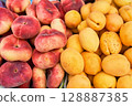 A colorful display of fresh peaches and juicy apricots at a local farmers market, showcasing seasonal fruits 128887385