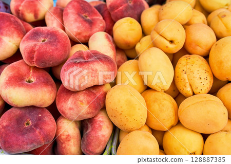 A colorful display of fresh peaches and juicy apricots at a local farmers market, showcasing seasonal fruits 128887385