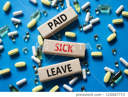 Paid Sick Leave symbol. Concept words Paid Sick Leave on wooden blocks. Beautiful blue background with pills. Healthcare and Paid Sick Leave concept. Copy space. 128887715