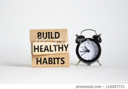 Healthy habits symbol. Concept word Build Healthy habits on wooden blocks with alarm clock. Beautiful white background. Healthy lifestyle and Healthy habits concept. Copy space 128887721