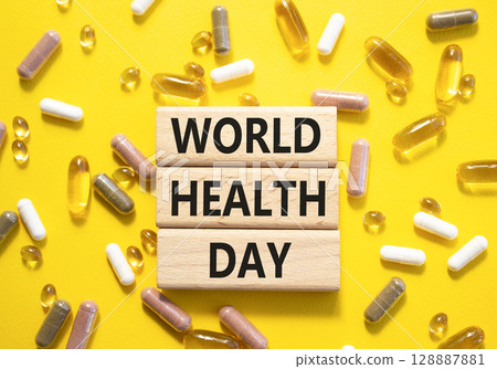 World Health Day symbol. Concept words World Health Day on wooden blocks. Beautiful yellow background with pills. Healthcare and World Health Day concept. Copy space. World Health Day symbol. Concept words World Health Day on wooden blocks. Beautiful yellow background with pills. Healthcare and World Health Day concept. Copy space. 128887881