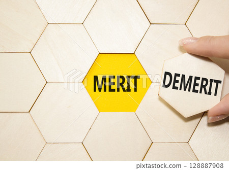 Merit or Demerit symbol. Concept word Merit or Demerit on wooden comb puzzle. Businessman hand. Beautiful yellow background. Business and Merit or Demerit concept. Copy space Merit or Demerit symbol. Concept word Merit or Demerit on wooden comb puzzle. Businessman hand. Beautiful yellow background. Business and Merit or Demerit concept. Copy space 128887908