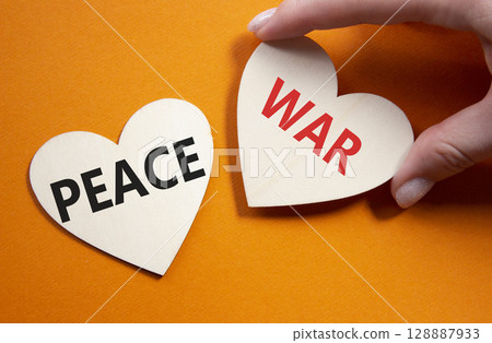 War or Peace symbol. Concept word War or Peace on wooden hearts. Businessman hand. Beautiful orange background. Business and War or Peace concept. Copy space War or Peace symbol. Concept word War or Peace on wooden hearts. Businessman hand. Beautiful orange background. Business and War or Peace concept. Copy space 128887933