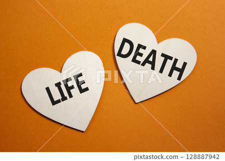 Life or Death symbol. Concept word Life or Death on wooden hearts. Beautiful orange background. Business and Life or Death concept. Copy space Life or Death symbol. Concept word Life or Death on wooden hearts. Beautiful orange background. Business and Life or Death concept. Copy space 128887942