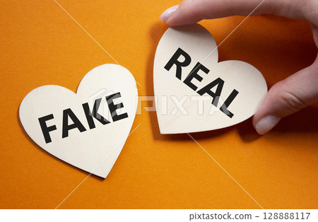 Real or Fake symbol. Concept word Real or Fake on wooden hearts. Beautiful orange background. Business and Real or Fake concept. Copy space 128888117