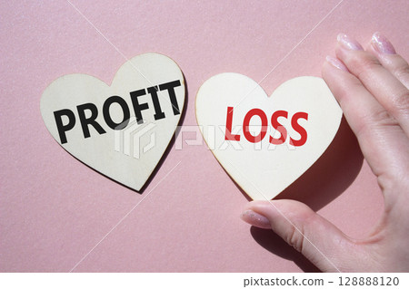 Profit or Loss symbol. Concept word Profit or Loss on wooden hearts. Businessman hand. Beautiful pink background. Business and Profit or Loss concept. Copy space 128888120