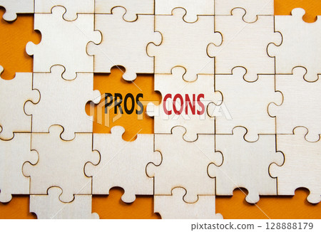 Pros vs Cons symbol. Concept word Pros vs Cons on wooden puzzle. Beautiful orange background. Business and Pros vs Cons concept. Copy space 128888179