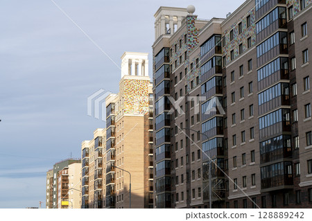 Facade of multi-storey buildings with windows and balconies. 128889242