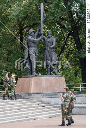 Krasnoyarsk, Russia - May 09 2024: A soldier in a helmet with a cloak holds a victory sword in his hands. Krasnoyarsk, Russia - May 09 2024: A soldier in a helmet with a cloak holds a victory sword in his hands. 128889244