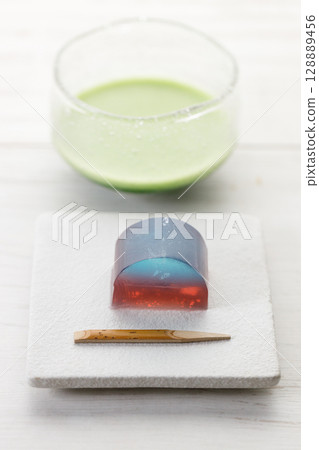 Cup of fresh matcha tea, green tea and Kingyoku can, traditional Japanese jelly confectionery on white wooden table. 128889456