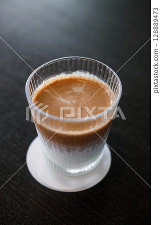 Glass of delicious cold milk chocolate on black wooden table background. Glass of delicious cold milk chocolate on black wooden table background. 128889473