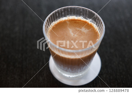 Glass of delicious cold milk chocolate on black wooden table background. 128889478
