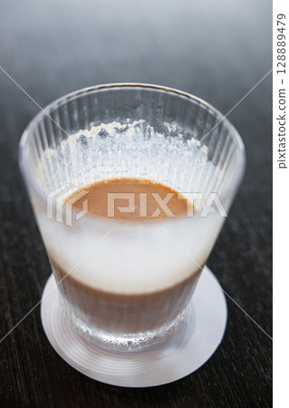 Glass of delicious cold milk chocolate on black wooden table background. 128889479