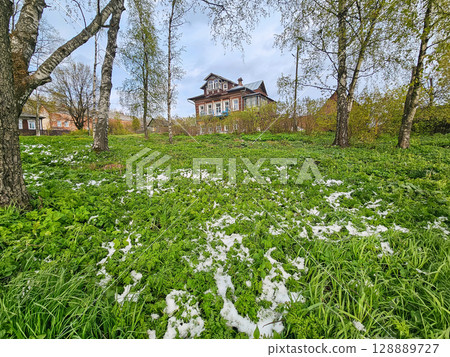 The spring green lawn is covered with snow 128889727