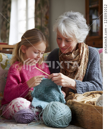 Grandmother showing granddaughter how to knit 128891012