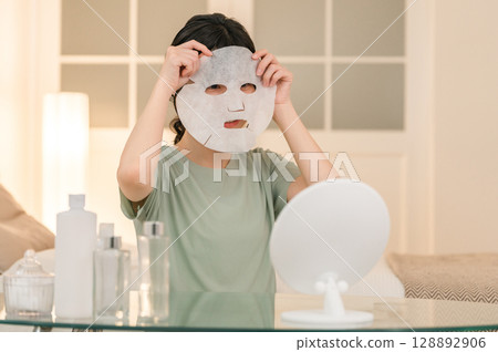 Young Asian woman using face pack at night (skin care, sheet mask, night care) Young Asian woman using face pack at night (skin care, sheet mask, night care) 128892906
