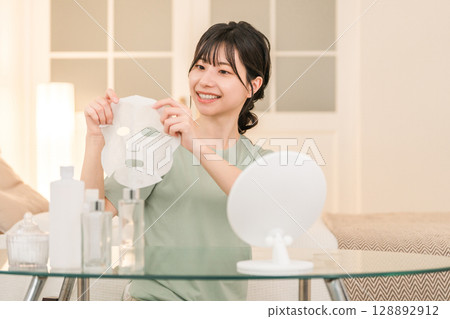 Young Asian woman using face pack at night (skin care, sheet mask, night care) 128892912