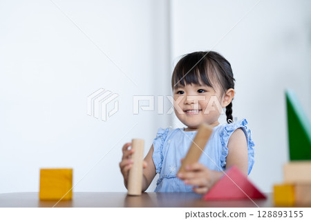 Smiling girl playing with building blocks 128893155