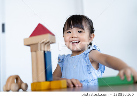 Smiling girl playing with building blocks 128893160
