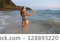 Woman stand knee-deep in sea on sunset. Girl on beach in green s Woman stand knee-deep in sea on sunset. Girl on beach in green s 128893220