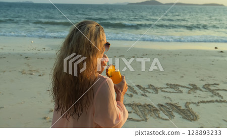 Woman walks on sunset on beach against background of sea. Girl i Woman walks on sunset on beach against background of sea. Girl i 128893233