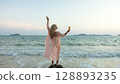 Woman stand on a reef rock stone in sea on sunset. Girl on beach Woman stand on a reef rock stone in sea on sunset. Girl on beach 128893235
