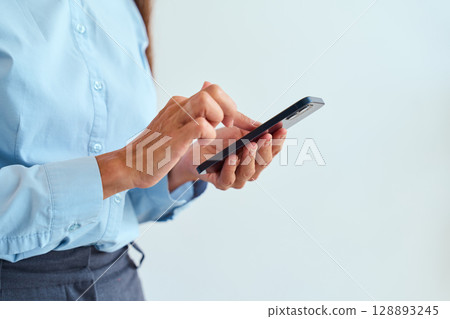Professional Woman Using Smartphone for Communication and Productivity in Work Environment 128893245