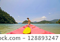 Man with sunglasses and hat rows pink plastic canoe along sea ag Man with sunglasses and hat rows pink plastic canoe along sea ag 128893247