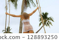 Sexual woman spends her vacation at the seaside. The girl is swinging on a swing. Sexual woman spends her vacation at the seaside. The girl is swinging on a swing. 128893250