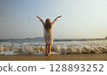 Woman is Wetting her Hair in a White Tunic on the Beach, near th Woman is Wetting her Hair in a White Tunic on the Beach, near th 128893252