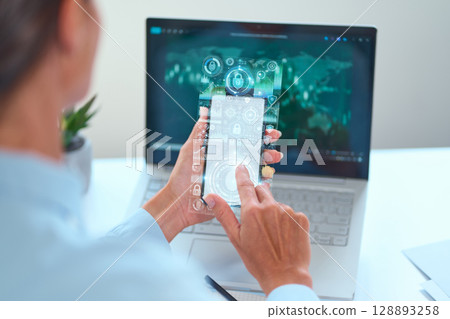 Person Interacting With Futuristic Digital Interface on Phone and Laptop Screen Person Interacting With Futuristic Digital Interface on Phone and Laptop Screen 128893258
