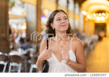 young woman walks through the evening streets of Barcelona 128893347