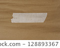 Single torn white tape on brown kraft paper background 128893367