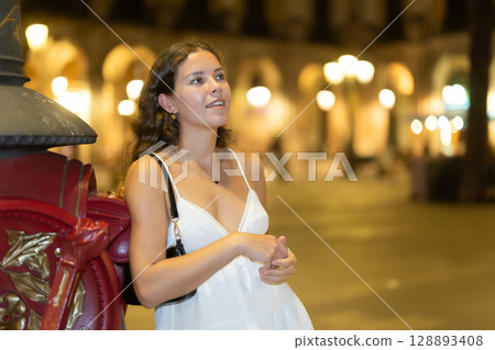 woman stands near a pole in the Plaza de Barcelona 128893408