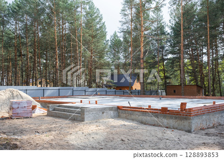 Concrete slab of foundation of house with laid pipes start of construction on project. Construction of cottages, design, engineering communications. Concrete slab of foundation of house with laid pipes start of construction on project. Construction of cottages, design, engineering communications. 128893853
