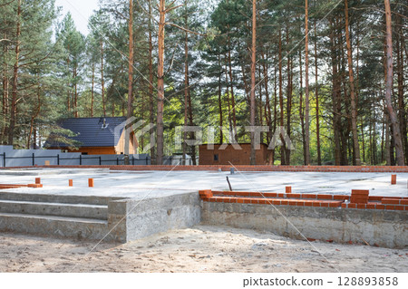 Concrete slab of foundation of house with laid pipes start of construction on project. Construction of cottages, design, engineering communications. 128893858
