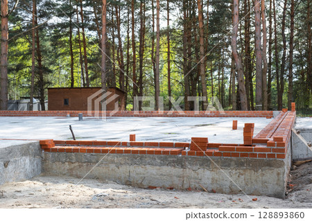 Concrete slab of foundation of house with laid pipes start of construction on project. Construction of cottages, design, engineering communications. 128893860