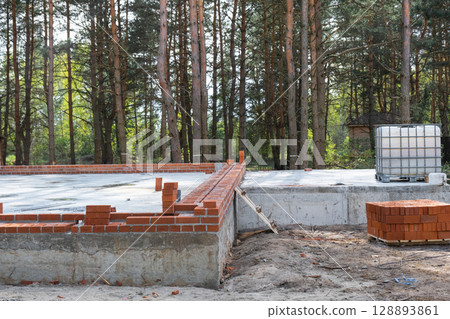 Concrete slab of foundation of house with laid pipes start of construction on project. Construction of cottages, design, engineering communications. Concrete slab of foundation of house with laid pipes start of construction on project. Construction of cottages, design, engineering communications. 128893861