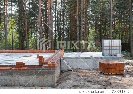 Concrete slab of foundation of house with laid pipes start of construction on project. Construction of cottages, design, engineering communications. Concrete slab of foundation of house with laid pipes start of construction on project. Construction of cottages, design, engineering communications. 128893862