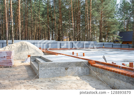 Concrete slab of foundation of house with laid pipes start of construction on project. Construction of cottages, design, engineering communications. 128893870