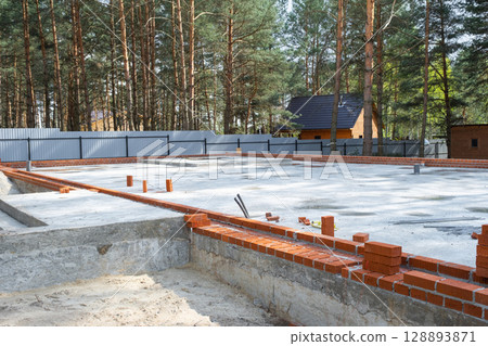 Concrete slab of foundation of house with laid pipes start of construction on project. Construction of cottages, design, engineering communications. 128893871