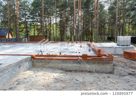 Concrete slab of foundation of house with laid pipes start of construction on project. Construction of cottages, design, engineering communications. 128893877