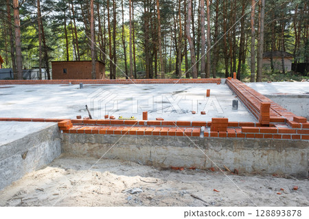 Concrete slab of foundation of house with laid pipes start of construction on project. Construction of cottages, design, engineering communications. 128893878